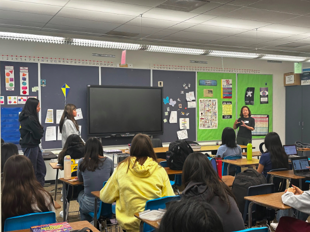 Abby Li (left) and Madeline Ng (right) ask guest speaker, Qing Zhang, questions at a club meeting.